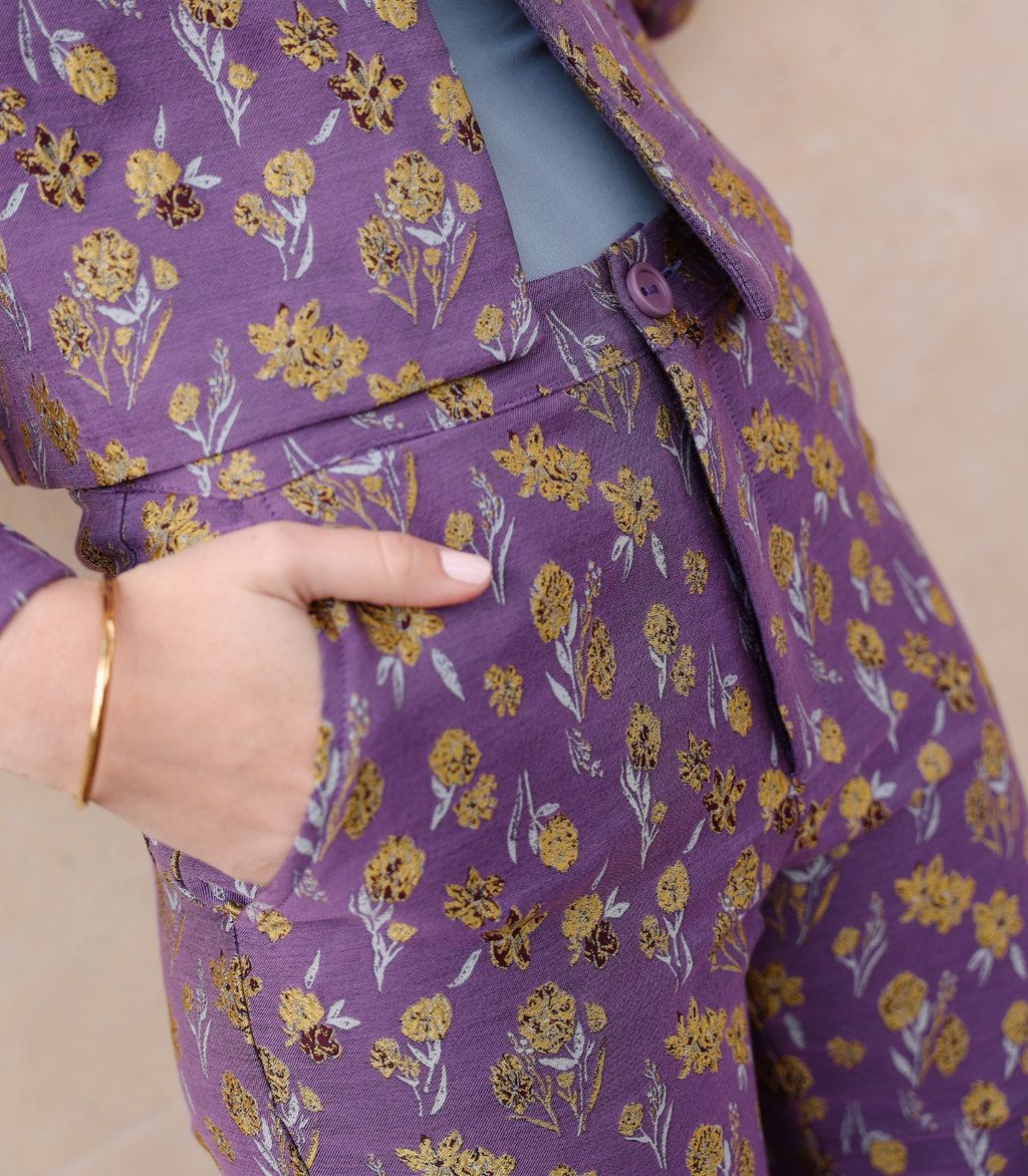 Close-up of the Harper trousers showing the intricate woven goldenberry floral texture and functional side pockets on lilac jacquard fabric.