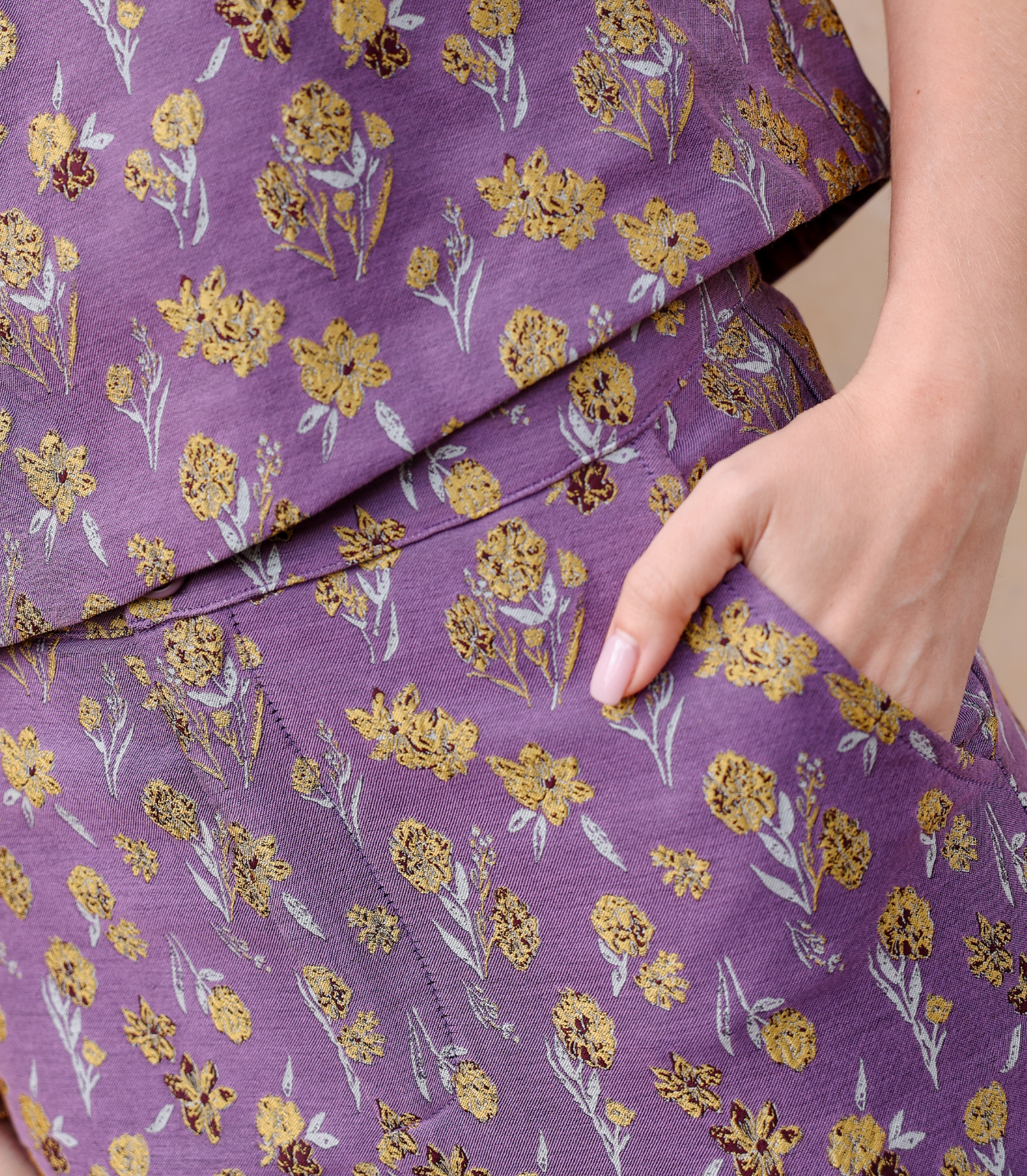 Close-up of the Harper trousers showing the intricate woven goldenberry floral texture and functional side pockets on lilac jacquard fabric.