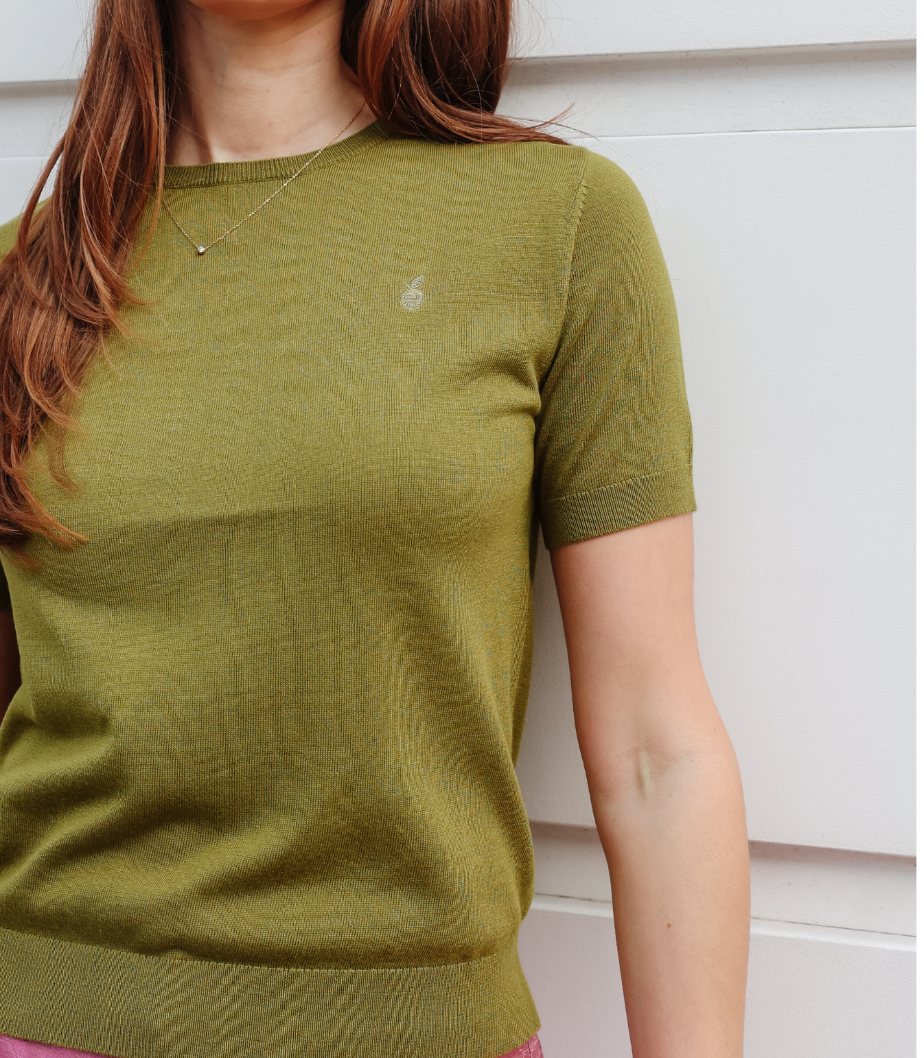 Close-up of the Kate Knit Top hem showing the signature gold Silk & Plum logo charm and premium ribbed waistband.